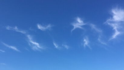 A deep blue sky with light clouds starting to form